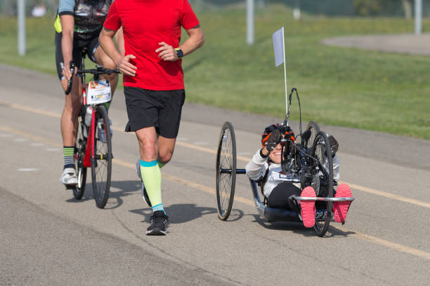 Disabled Athlete who Trains with her Hand Bike with Cyclist and Runners at her Side Parma, Italy - October 2020: Disabled Athlete who Trains with her Hand Bike with Cyclist and Runners at her Side. paralympic games stock pictures, royalty-free photos & images