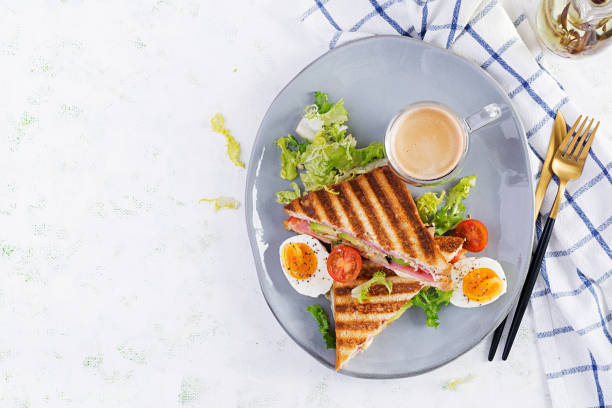 panini sanduíche de clube grelhado com presunto, tomate, queijo, abacate e xícara de café. delicioso café da manhã ou lanche. vista superior, flat lay - club sandwich sandwich salad bread - fotografias e filmes do acervo