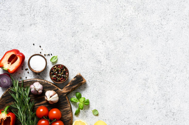 istock Brown cutting board with spices and vegetables on a light, a concrete kitchen table. Layout. 1291728760