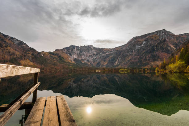 istock wooden jetty with reflection and weak sun in the mountains with a mountain lake 1291729090