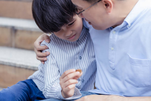 istock Hunger child look at coin and get sad while father embracing and console his son during they sitting in city Parent and son get homeless because of economy crisis They get hopeless Financial problem 1291731225