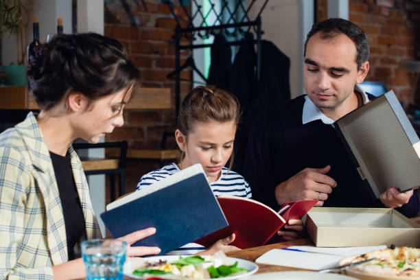 istock A girl doing her homework at the kitchen table with her parents 1291731523