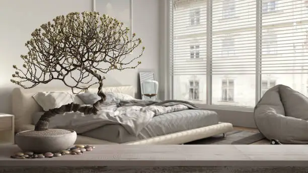 Photo of Vintage wooden table shelf with pebble and potted bloom bonsai, white flowers, over modern bedroom, panoramic window, bed with pouf, interior design, clean architecture concept idea