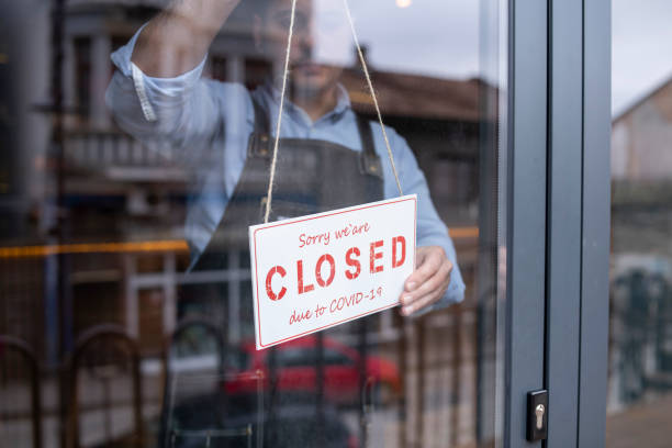 Man closing his small business during COVID-19 pandemic. Sadness man closing his small business during COVID-19 pandemic. closed sign stock pictures, royalty-free photos & images