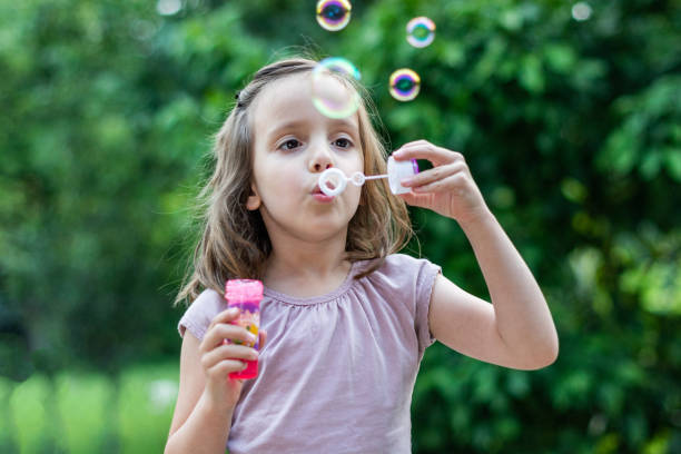 istock Cute little girl blowing soap bubbles 1291734668