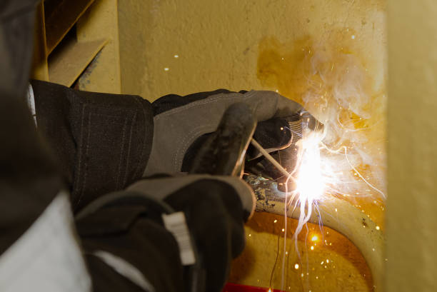 istock Professional welder welding with electric old metal pipes for heating. Old heating system renovation concept 1291736593