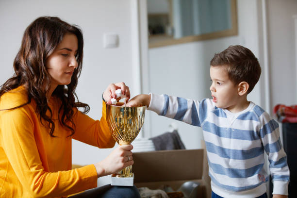 istock Mother playing with toddler during relocation, filling cup with packing peanut 1291738580