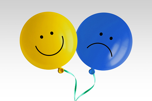 Happy and sad balloon tied together on white background - Concept of bipolar disorder