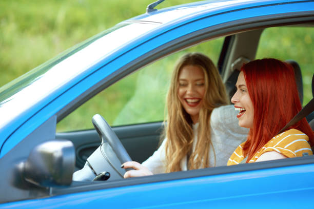 istock Two women laughing inside of car, driving 1291740512