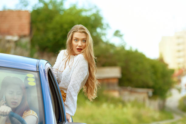 Beautiful young female is fixing her make-up near the vintage car. Photo in vintage style