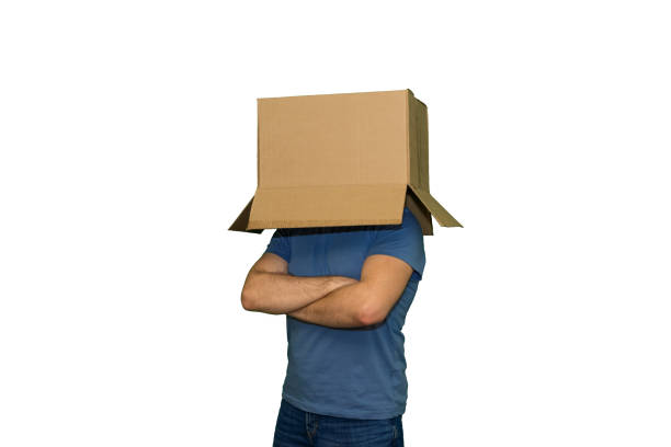 Young man with a cardboard box on his head folded his arms on his chest, isolated on white background