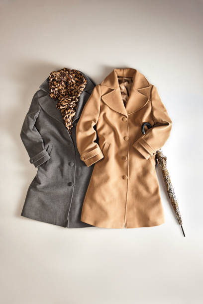Fashionable women’s coats on beige background