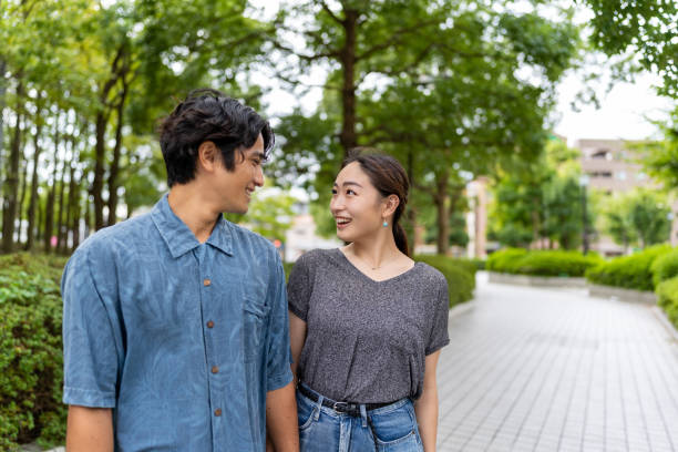Asian married couple standing outside, looking eye to eye