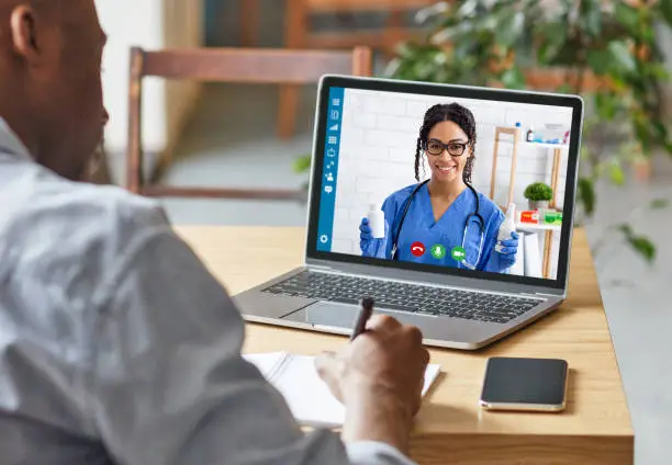 Photo of Medical services online. African American guy having consultation with doctor on laptop