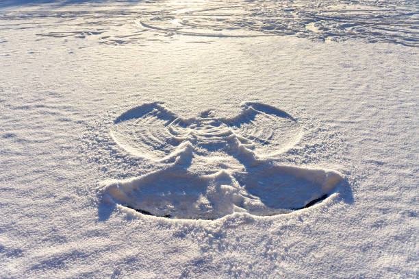 print of a snow angel on fresh white snow and frozen lake. Abstract, winter fun print of a snow angel on fresh white snow and frozen lake at sunset. Abstract background, Christmas, twinter fun, snowy snow angels stock pictures, royalty-free photos & images