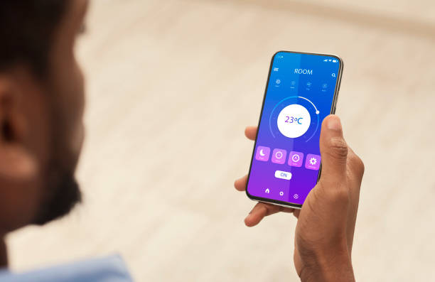 istock African American guy holding cellphone with smarthome mobile app on screen, creative collage 1291747736