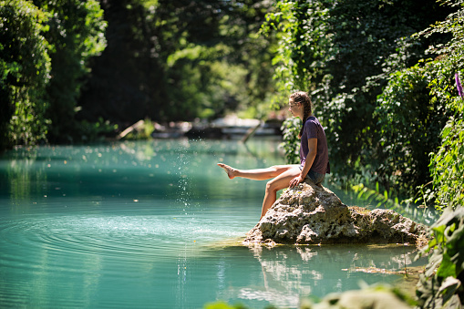 Family hiking near river Elsa in Colle di Val d'Elsa, Tuscany. Teenage girl is sitting on a rock in beautiful river Elsa in Tuscany, Italy\nNikon D850