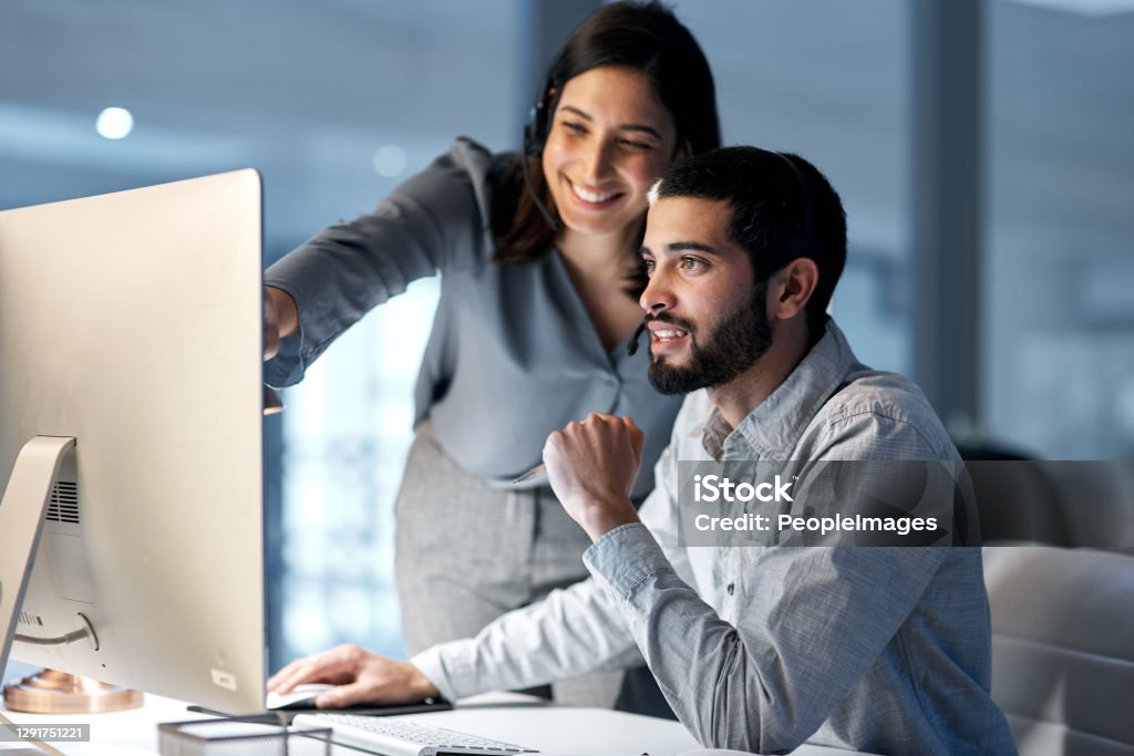 The sales department scores again Shot of a young woman helping her colleague in a call centre late at night Technology Stock Photo