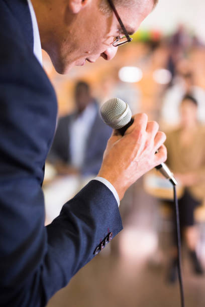istock Male coach holding microphone at conference hall 1291753410