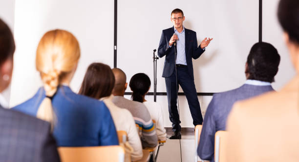 istock Confident lecturer speaking to businesspeople at seminar 1291753636