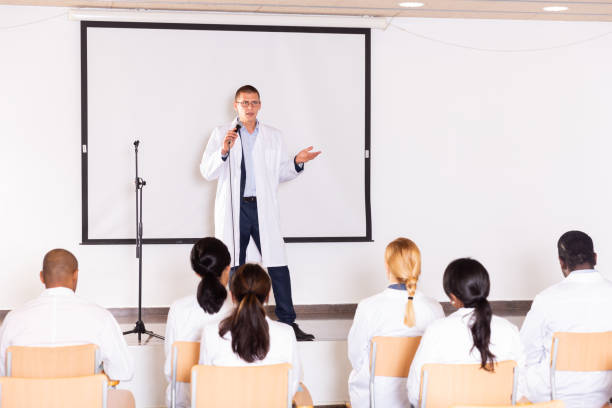 istock Speaker in white coat giving presentation at medical conference 1291753708