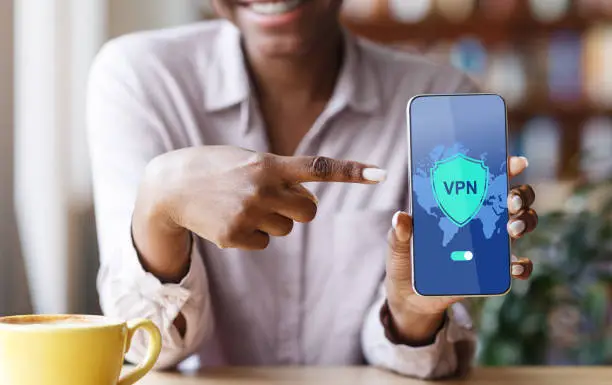 Photo of VPN App. Black Woman Pointing At Smartphone With Virtual Private Network Application