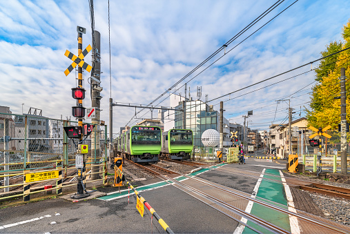 tokyo, japan - december 06 2020: Two Japan Railway E235 series trains crossing each other passing over the level crossing of the Yamanote line called Nakazato railroad crossing II located at Komagome.
