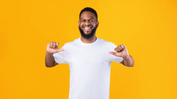 felice uomo africano che punta i pollici su se stesso su sfondo giallo - solo un uomo foto e immagini stock