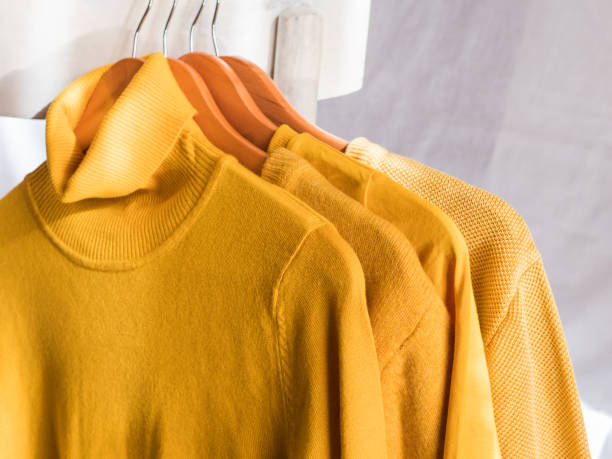 istock Yellow illuminated color winter sweaters on hangers 1291756495