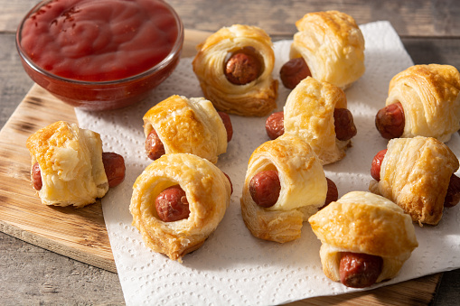 Pigs in blankets. Mini sausages wrapped in puff pastry with ketchup sauce.