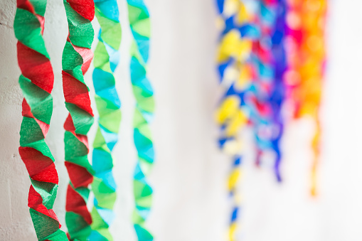 Christmas chains from tissue paper for Christmas tree hangs on on white wooden hanger. White, brick wall in background. Krakow in Poland. No people. Close shot.