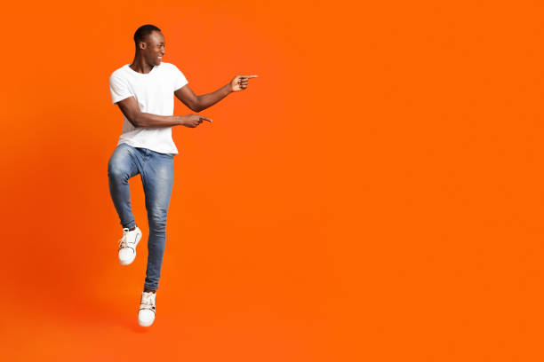 istock Excited black guy jumping up and showing copy space 1291759946