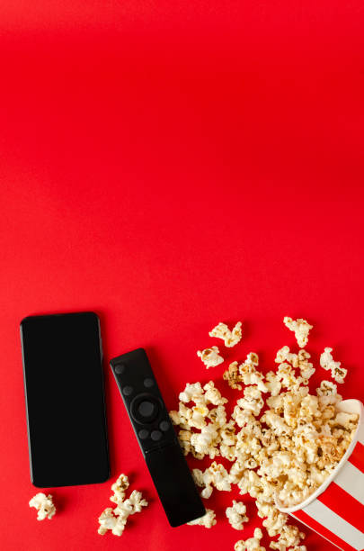 vertical image.top view of smartphone, clicker and popcorn on the red background.empty space - remote television movie box imagens e fotografias de stock