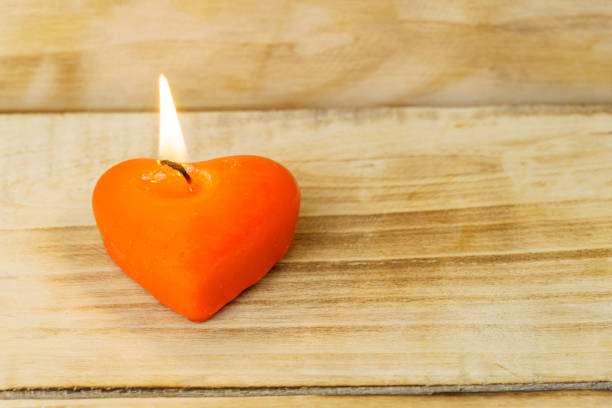 istock Red burning heart shaped candle with copy space on wooden background. 1291762737