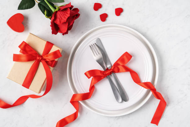 istock Plate with tableware, ribbon, gift and roses for Valentine's Day special meal concept. 1291763705