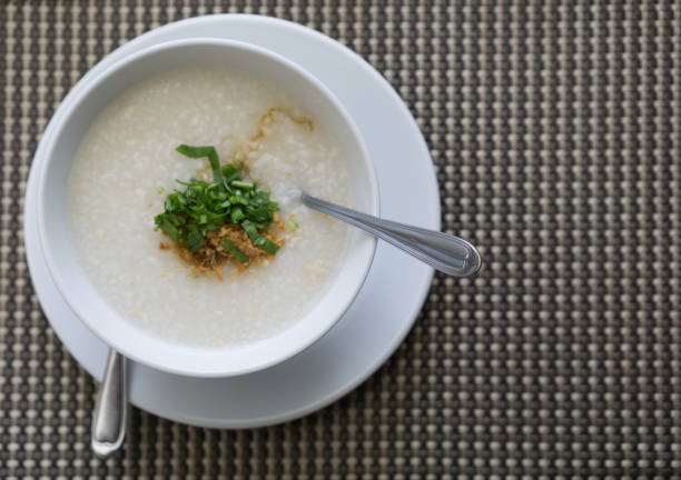 istock Boiled rice in a white bowl with vegetables sprinkled on top with a spoon, placed on a gray background, Top view. 1291764210