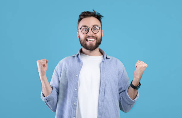 istock Excited bearded guy making YES gesture, smiling, clenching fists on blue studio background, panorama 1291764261