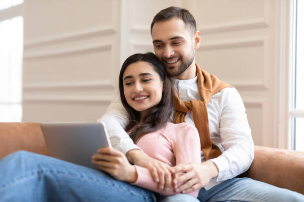istock Happy Modern Arab Couple Using Digital Tablet Sitting At Home 1291764359