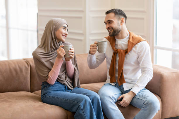 istock Happy Muslim Couple Drinking Coffee Sitting On Sofa At Home 1291765017