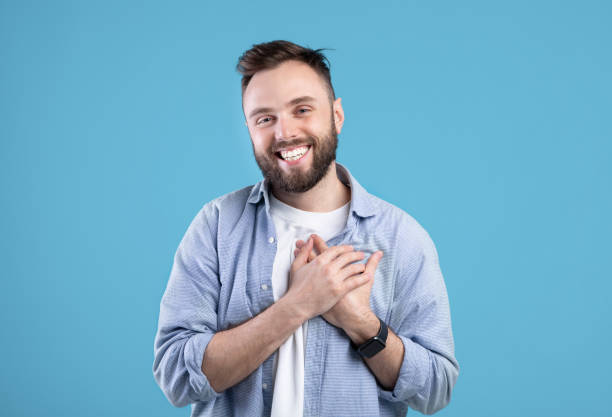 istock Cordial millennial guy holding his hand on chest, expressing gratitude and positive emotions on blue studio background 1291765110