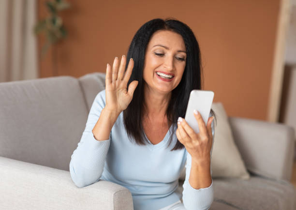istock Mature woman using mobile phone for video call and waving 1291766421