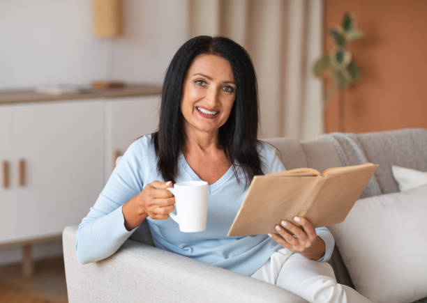 istock Mature lady holding cup of coffee and book 1291766437