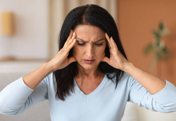 istock Mature brunette woman touching her temples feeling headache 1291766446