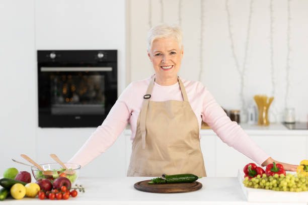 istock Happy Senior Lady Cooking In Kitchen Making Salad At Home 1291766964