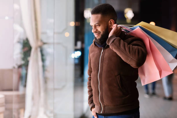 istock Black guy with shopping bags looking at mall window 1291767002
