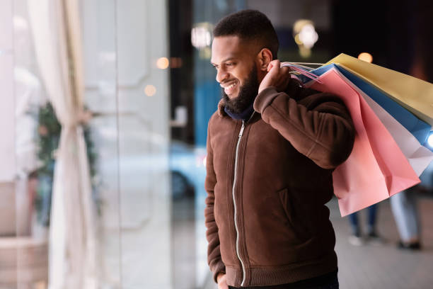 istock Black bearded man with shopping bags looking at mall window 1291767068