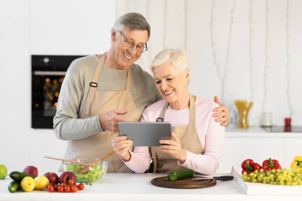 istock Cheerful Elderly Couple Using Digital Tablet Cooking Together In Kitchen 1291768068