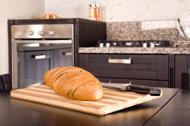 close up sliced bread and cutting board with knife on wooden kitchen table in modern domestic kitchen
