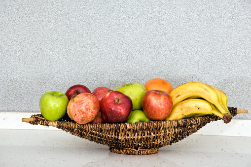 Mixed fruit in wicker bowl on granite countertop of domestic kitchen