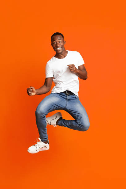 istock Black guy jumping in the air and showing funny figures 1291770127